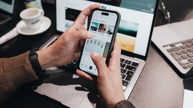 Mains tenant un smartphone au-dessus d'un ordinateur portable ouvert