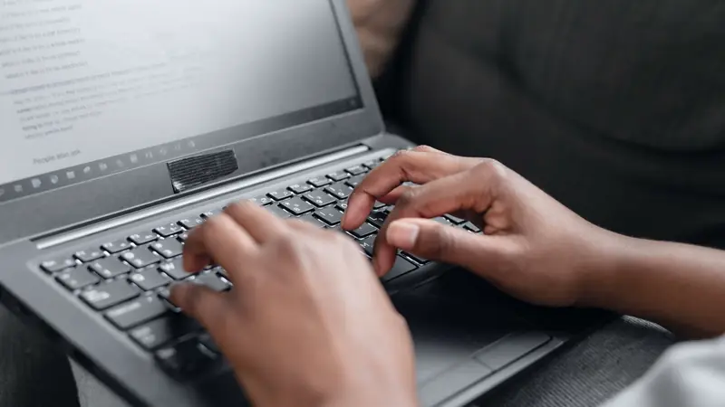 Mains posées sur le clavier d'un ordinateur portable, écran affichant une page de résultats