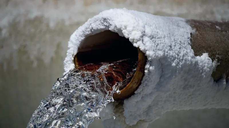 Eau jaillissant d'un tuyau métallique rouillé couvert d'une épaisse croûte de sel blanc