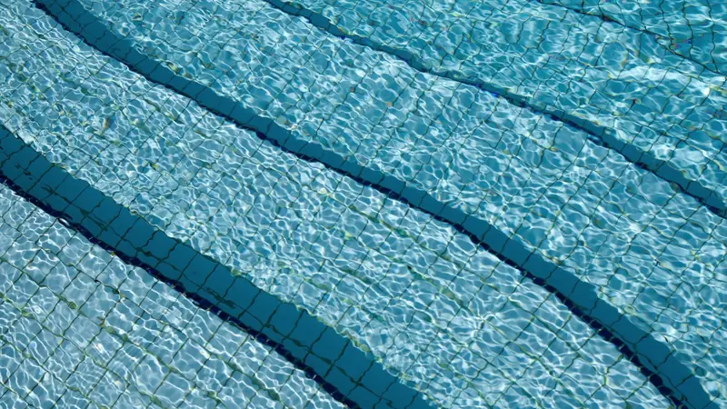 Fond carrelé d'une piscine vu à travers une eau claire et ondulante