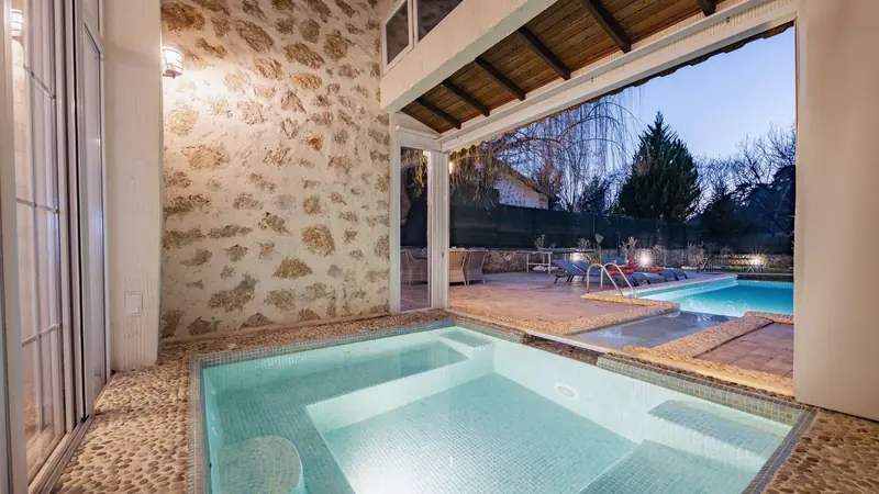 Petit bassin maçonné revêtu de mosaïque turquoise, bordé de galets, ouvert sur une piscine extérieure