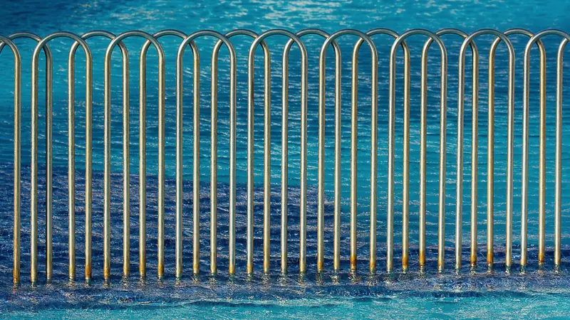 Garde-corps en tubes métalliques arrondis dressé dans l'eau bleue d'une piscine