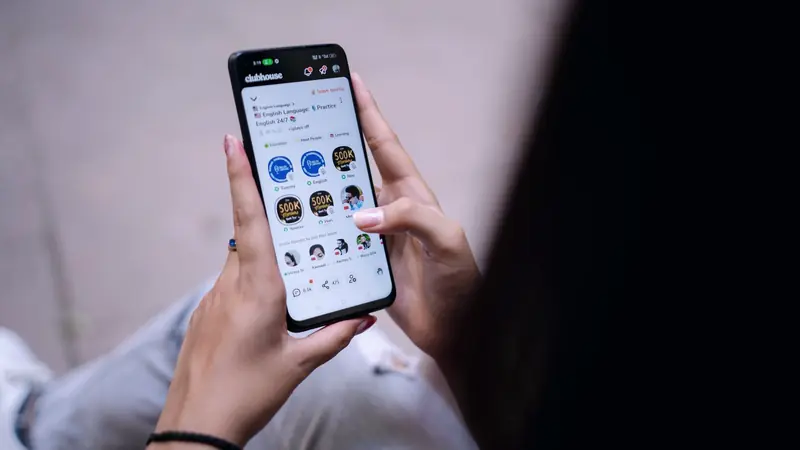Femme tenant à deux mains un smartphone ouvert sur une application de réseau social